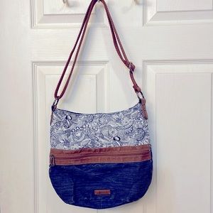 This is a blue Sakroots purse. It can be worn on the shoulder or crossbody.